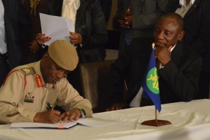 With Ramaphosa looking on, Kamoli signs his pledge to keep the peace - and head into de facto exile? (Photo: mjj)